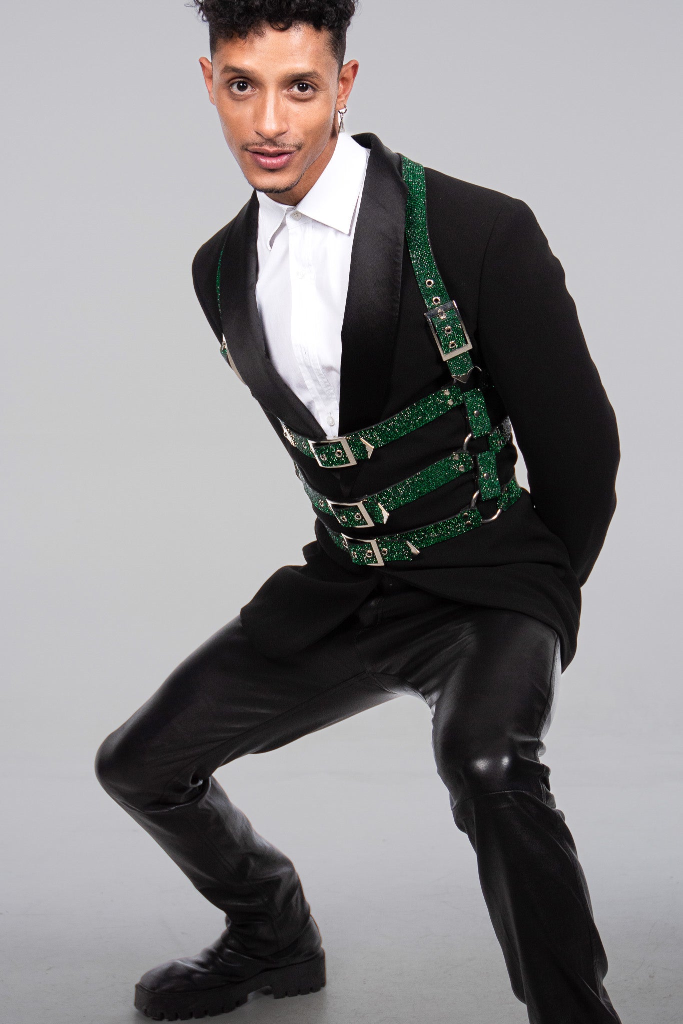 The handsome male model is wearing the cage harness by the cool new fashion brand Lorand Lajos ontop of a very elegant mens dinner jacked. the look shines because of the many crystals and rhinestones in emerald green