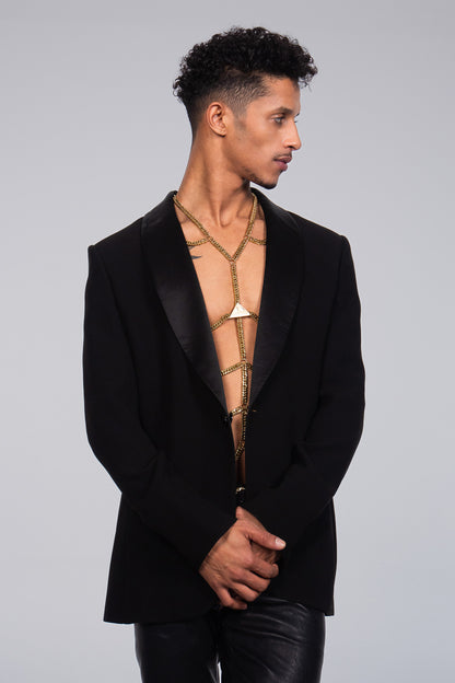 The picture shows the accessory body chain in gold by Lorand Lajos. The chain is shown on a handsome, young, fashionable, man with an elegant suit jacket