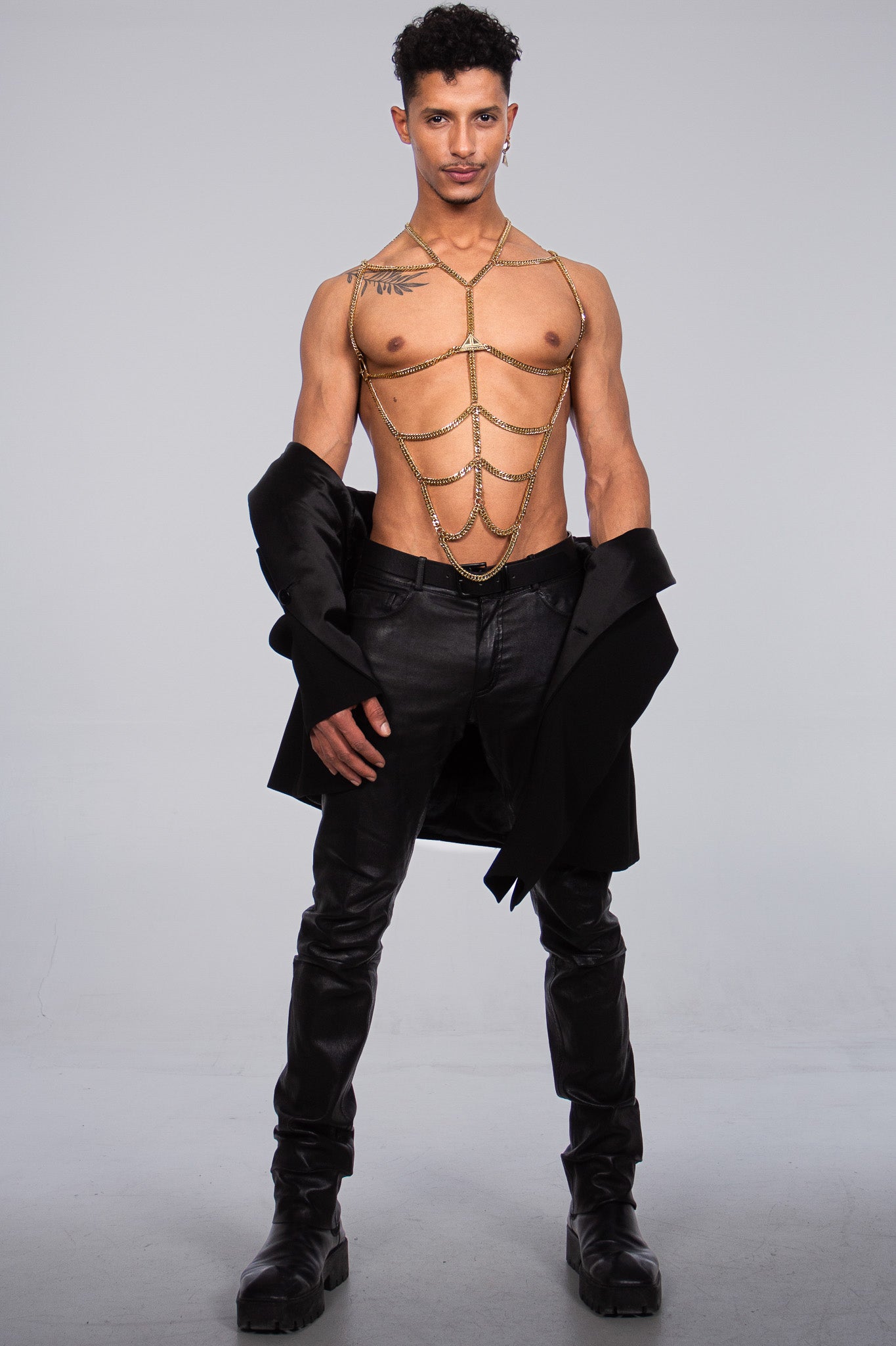 the sparkly gold body chain accessory by Lorand Lajos in this picture is enhancing the shape of the models six pack. the model is topless. He is a masculin, muscular young men.