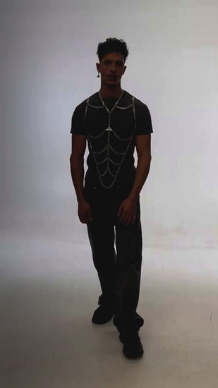 Te video shows the body chain accessory by the fashion brand Lorand Lajos on a handsome male model. the shape of the shiny silver chain draws a six pack on top of a gray T-shirt. Together with Jeans a modern street stile look is created